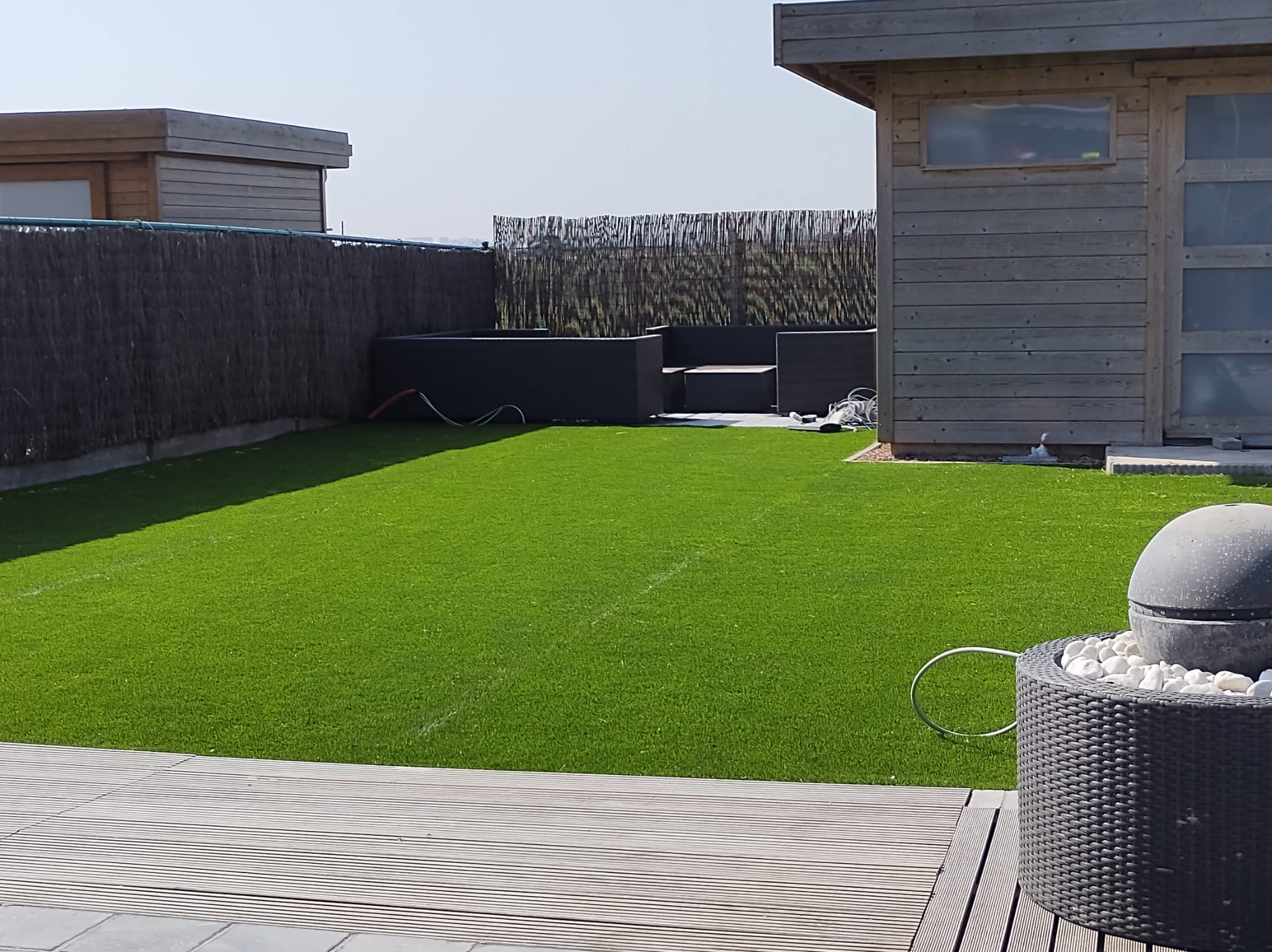 Kunstgras met houten tuinhuis en terrasvlonder